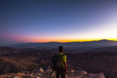 Rear view of man standing on mountain against sky