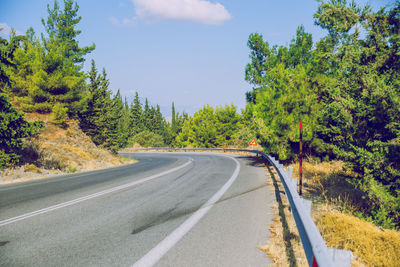 Empty road amidst trees against sky