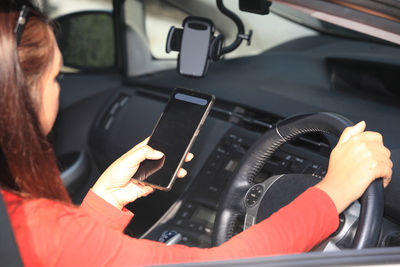Midsection of woman using smart phone in car