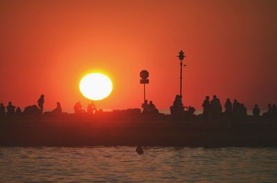 Silhouette of people in calm sea at sunset