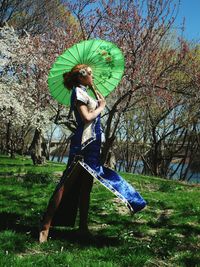 Woman holding umbrella while walking on grass