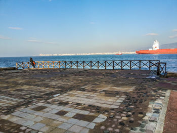 Person standing next to sea against cloudy sky