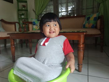 Portrait of cute boy sitting on chair at home