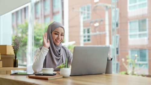 Portrait of young woman using mobile phone in office