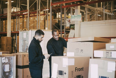Male manual workers analyzing cardboard box at warehouse
