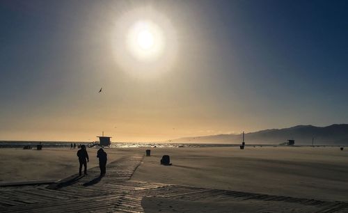 People on beach against sky during sunset