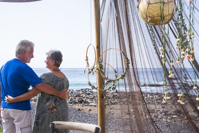 Rear view of loving senior couple standing at beach