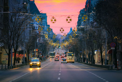 Cars on road amidst buildings in city at dusk