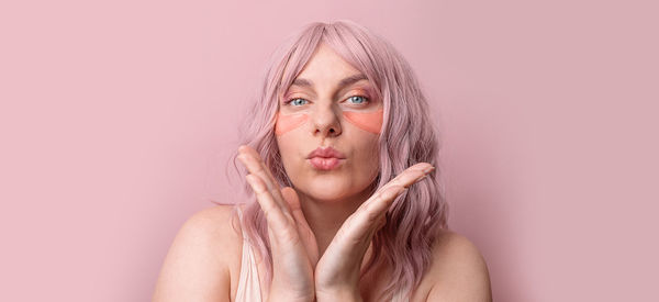 Portrait of woman gesturing against colored background