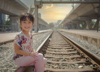 Portrait of girl sitting on railroad track