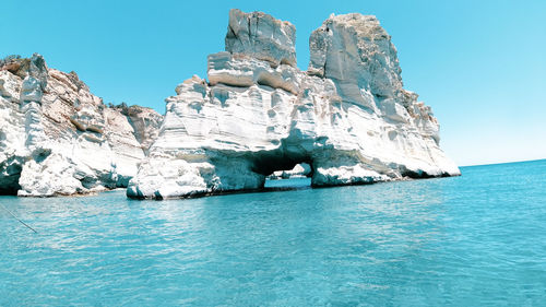 Panoramic view of rock formation in sea against clear blue sky