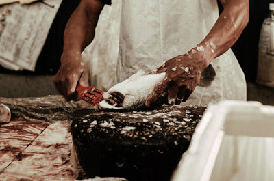 Midsection of woman cleaning fish at market for sale