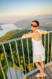 Portrait of woman wearing sunglasses while standing at observation point against landscape