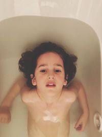 High angle portrait of naked girl sitting in bathtub