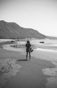 Rear view of man on beach against clear sky