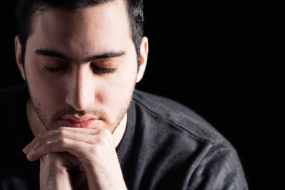 Close-up portrait of young man against black background