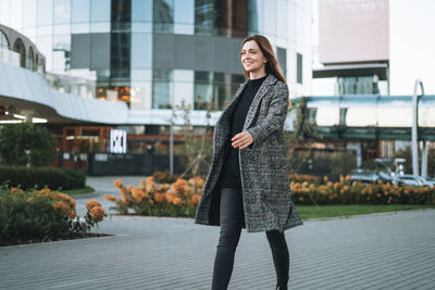 Portrait of young woman standing in city