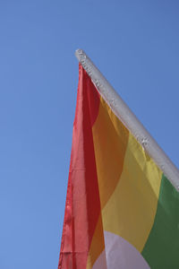 Low angle view of flags against clear blue sky