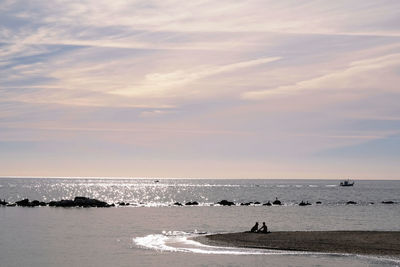 Silhouette of man and dog in the distance by the beach 