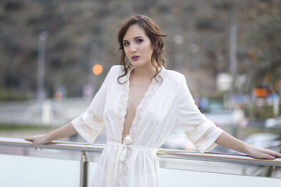 Portrait of beautiful young woman standing at balcony