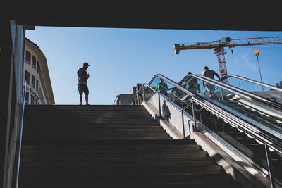 Low angle view of man standing on staircase against sky