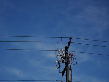 Low angle view of electricity pylon against blue sky