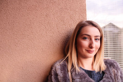 Portrait of a smiling young woman against wall