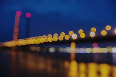 Defocused image of illuminated bridge over river at night