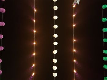 Low angle view of illuminated light bulbs hanging at night