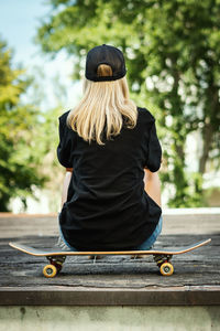 Rear view of woman sitting on skateboard