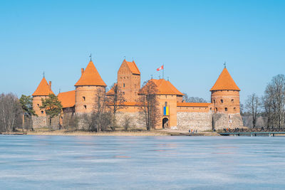 Medieval castle of trakai, vilnius, lithuania in winter with frozen lake and ukrainian flag