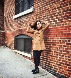 Woman standing against brick wall