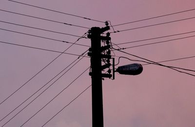 Low angle view of silhouette electricity pylon against sky