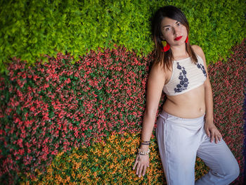 Beautiful young woman standing by flower plants