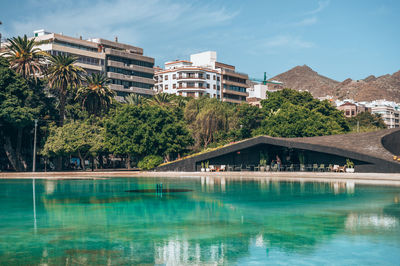 Buildings by lake against sky