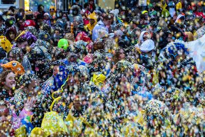 Crowd throwing colorful confetti in city during celebration