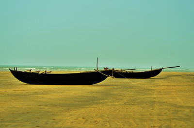 Boat moored on beach against clear sky