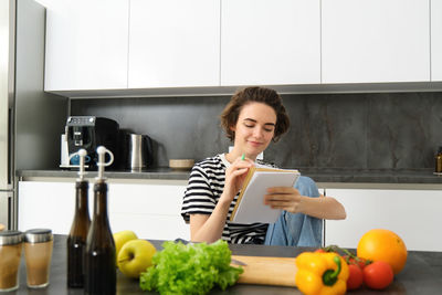 Portrait of young woman holding food at home
