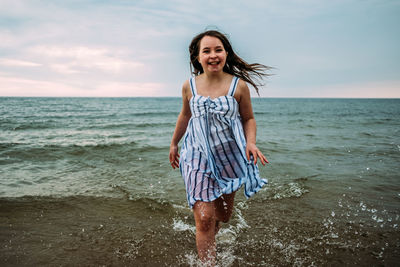 Young girl running through water in clothes in lake michigan