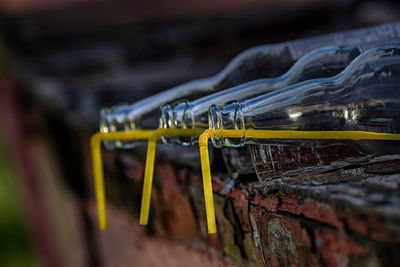 Close-up of bottles with drinking straw on retaining wall