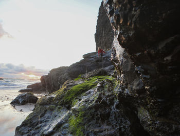 Low angle view of person on rock formation in sea