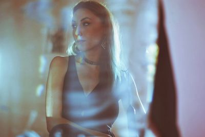 Young woman looking away seen through glass at home