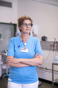 Female doctor with arms crossed looking away while standing in hospital