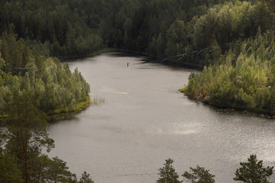 A tightrope walker on a slackline over a picturesque forest lake. extreme sports theme