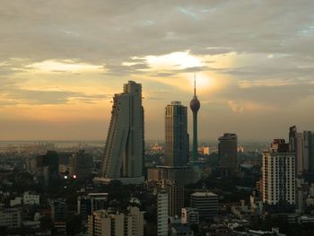 Modern buildings in city against sky during sunset