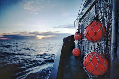 Red buoy on tugboat in sea against sky at dusk