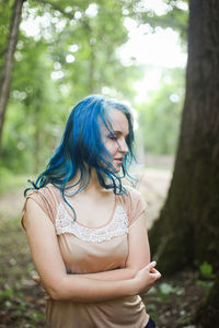 Mid adult woman standing against trees in forest