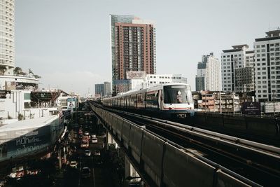 Urban train against city building against sky