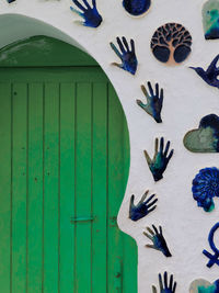 Green wooden door decorated with mosaic decors on the wall around it