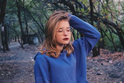 Fashionable young woman standing in forest